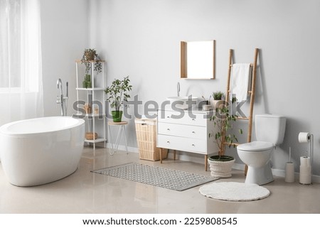Interior of light bathroom with drawers, toilet bowl and laundry basket Royalty-Free Stock Photo #2259808545
