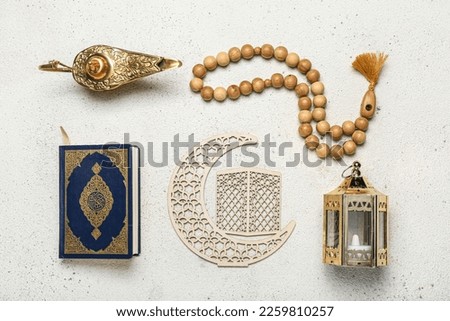 Aladdin lamp, Koran, Muslim lantern, crescent and prayer beads for Ramadan on light background Royalty-Free Stock Photo #2259810257