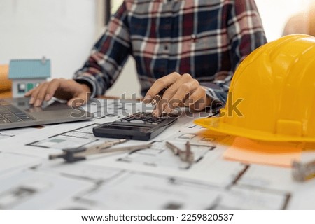 Close up Architect or Engineer using on calculator for calculating value estimating for safety with the drawing construction building