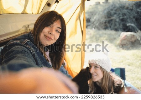 Couple taking a selfie. Women having fun together in a van. Winter vacations and relationship concept.