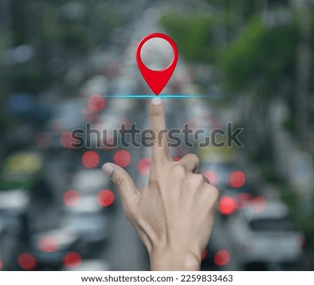 Hand pressing map pin point location button over blur of rush hour with cars and road in city, Map pointer navigation concept