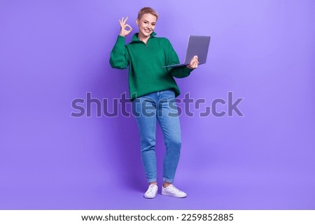 Full length photo of shiny confident woman dressed green pullover typing modern gadget showing okey isolated purple color background