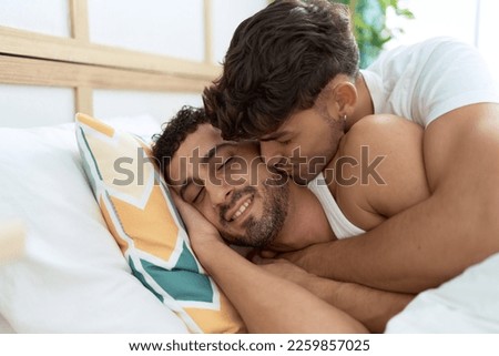 Two hispanic men couple lying on bed hugging each other and kissing at bedroom Royalty-Free Stock Photo #2259857025