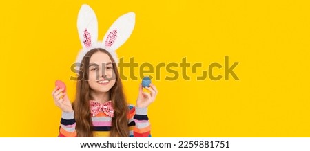 smiling teen child in bunny ears and bow tie hold easter eggs on yellow background. Easter child horizontal poster. Web banner header of bunny kid, copy space.