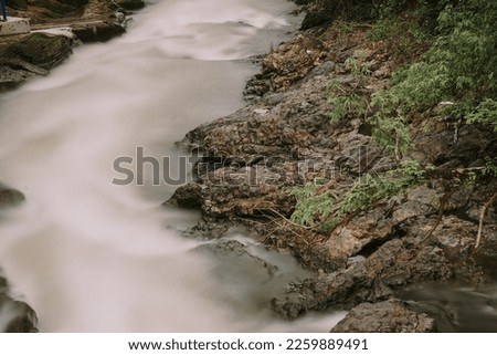 picture of a river with swift water flow and pillow lava  rocks in Yogyakarta, Indonesia, long exposure shot, no people
