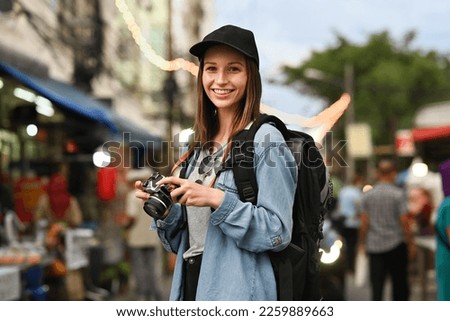 Portrait of hipster female tourist with digital camera standing in night market in Chiang Mai northern Thailand