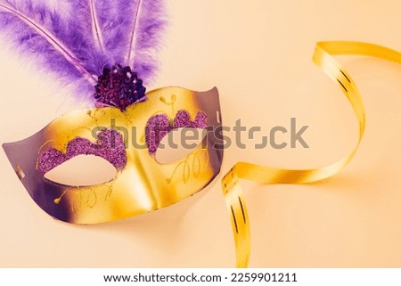 Happy Purim carnival decoration. Top view venetian ball mask with purple feather on pastel background, Jewish Purim and Mardi Gras in Hebrew, holiday background banner design, Masquerade party