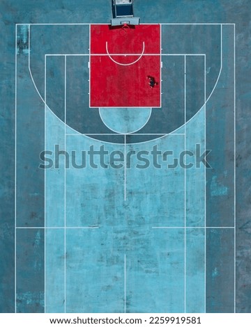 A vertical aerial shot of a basketball court with a player improving his skills