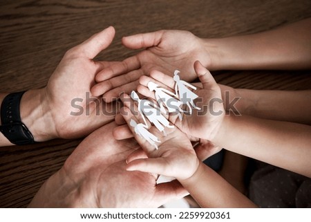 Hands, paper cutout family and house on table for sign, symbol or icon of support, love and solidarity. Art design with mother, father and children together for safety, trust and insurance in home