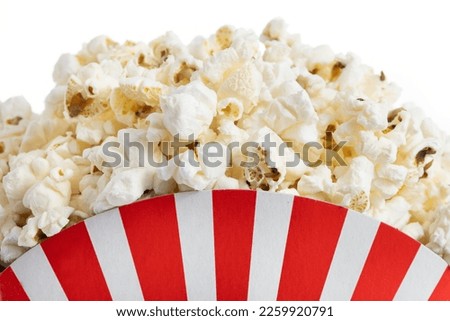 Popcorn in red and white striped cardboard bucket isolated on white background. Close up