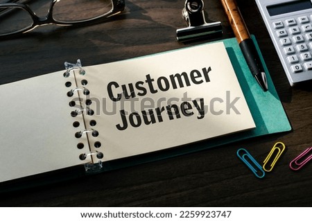 There is a notebook with the word Customer Journey. It is an eye-catching image.