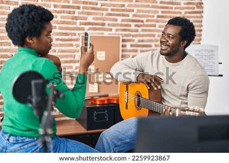African american man and woman music group make photo holding spanish guitar at music studio