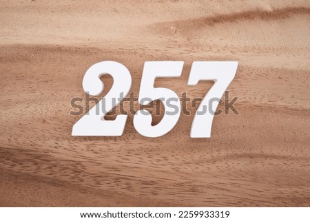 White number 257 on a brown and light brown wooden background.