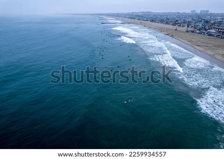 A drone shot of hte Surfers hitting the waves of the sea