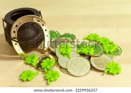 A closeup shot of a Saint Patrick's day hat and a pot of gold coins on a wooden table