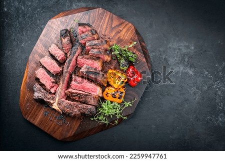 Traditional barbecue dry aged wagyu porterhouse beef steak offered with paprika and chili as top view on modern design wooden board  Royalty-Free Stock Photo #2259947761
