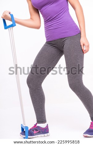 Healthy young sportswoman does the exercise holding in  hand and leg elastic  isolated on white background with copy place selective focus