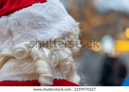 A closeup of the back of a Santa Claus in the street on a blurry background