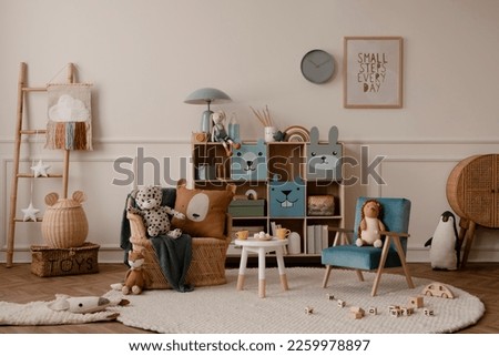 Warm and cozy kids room interior with mock up poster frame, beige wall with stucco, colorful sideboard, braided armchair, plush toys, brown pillow and personal accessories. Home decor. Template.  Royalty-Free Stock Photo #2259978897