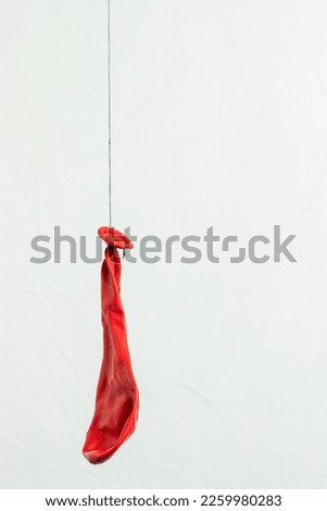 Deflated red balloon. Hanging on a black thread. Royalty-Free Stock Photo #2259980283