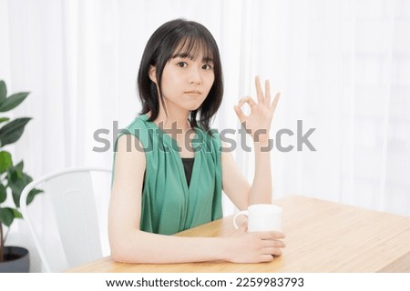 A young woman making an OK sign in the living room