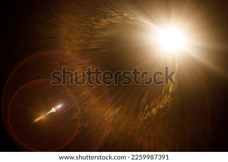 Easy to add lens flare effects for overlay designs or screen blending mode to make high-quality images. Abstract sun burst, digital flare, iridescent glare over black background. Royalty-Free Stock Photo #2259987391