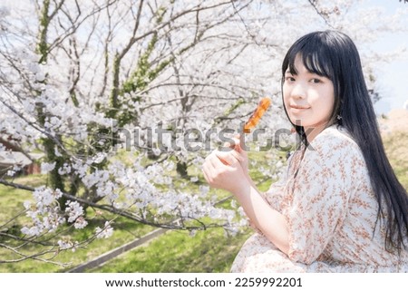 A woman who enjoys cherry blossom viewing while holding dumplings.