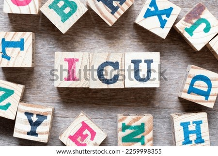 Alphabet letter block in word ICU (abbreviation of intensive care unit) and another letter on wood background