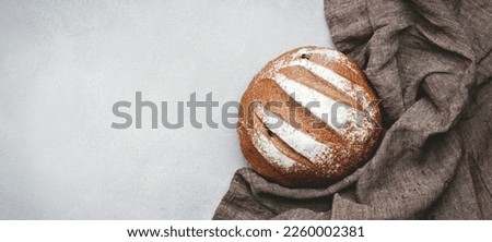 Rye sourdough bread, whole loaf,  kitchen linen towel. Gray table background, top view