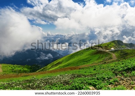 Amazing mountain landscape on sunny summer day with a cloudy sky. Mountains with green grass covered with snow against a cloudy sky in Caucasus highlands. 