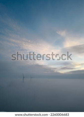 Aerial view of wind turbines or windmills farm field in industry factory with fog. Power, sustainable green clean energy, and environment concept. Nature preservation innovation. High quality photo