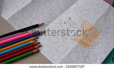 a kid drawing an Easter bunny on a white paper with pencil.