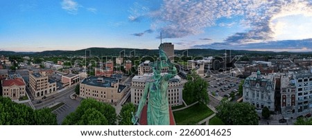 A panoramic aerial shot of the cityscape of downtown Binghamton, with a green statue in the middle