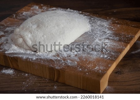 the dough lies on a wooden cutting board sprinkled with flour
