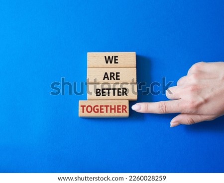 We are stronger together symbol. Wooden blocks with words We are stronger together. Businessman hand. Beautiful blue background. We are stronger together concept. Copy space.