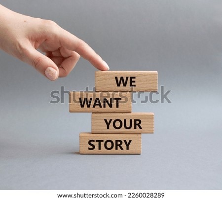 We want your story symbol. Concept words We want your story on wooden blocks. Beautiful grey background. Businessman hand. Business and We want your story concept. Copy space.