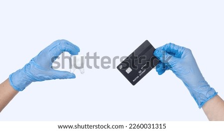 Female dentist hand in blue gloves holds dentist Tooth model and credit card. Light background. Concept of Cost of dental treatment..