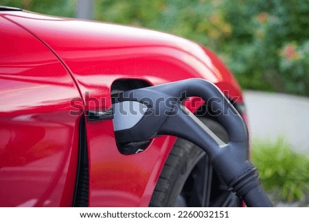 A closeup of a red electric car on a charge