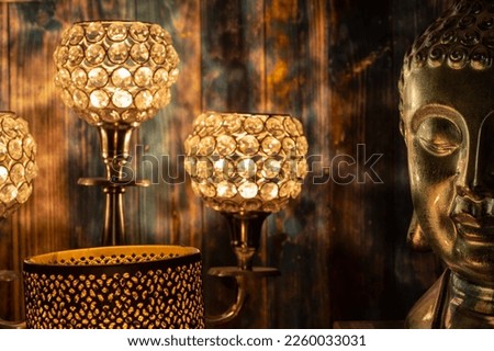 A closeup shot of a golden Buddha head figurine near glowing lamps