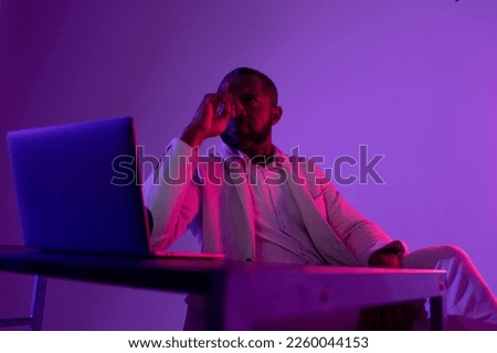 Photo of pensive man in white suit thinking about new web security project in night office near computer. neon light