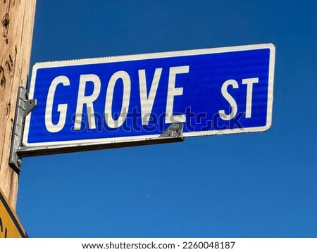 Grove St. white and blue street sign against a clear blue sky backdrop.