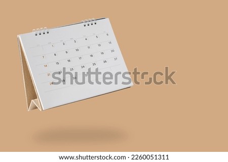 White paper desk calendar flipping page isolated on brown background