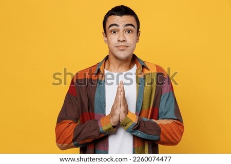 Young middle eastern man 20s wear casual shirt white t-shirt hold hands folded in prayer gesture, begging about something isolated on plain yellow background studio portrait People lifestyle concept Royalty-Free Stock Photo #2260074477