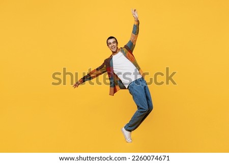 Full body young middle eastern man 20s he wear casual shirt white t-shirt look camera with outstretched hands dance stand on toes isolated on plain yellow background studio People lifestyle concept
