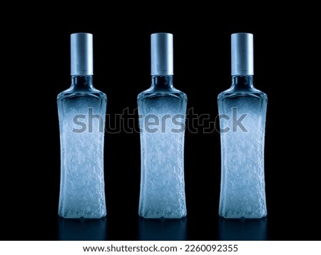 Frozen bottle of vodka covered with frost, close-up isolated on black
