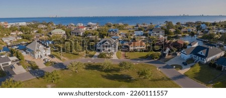 Intracoastal neighborhood with single-family homes at Navarre, Florida. Panoramic aerial view of street at the front of houses with waterways in between against the bay and sky background. Royalty-Free Stock Photo #2260111557