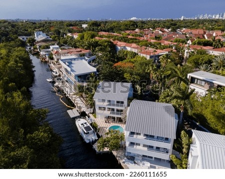 Row of three-storey houses with private docks in a coastal neighborhood at Miami, Florida. There is a small waterway on the left near the houses in an aerial shot view.