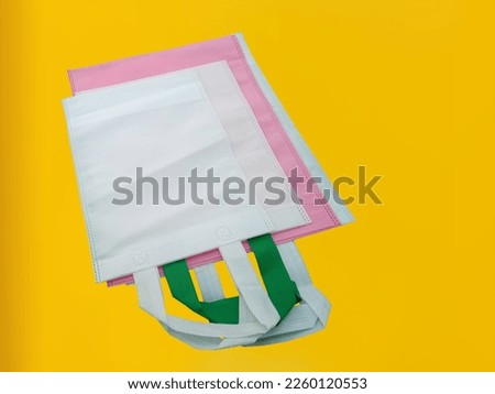 biodegradable environmental Non-Woven Grocery Shopping reusable bags with a yellow background. Tote sustainable ECO Bags. Proudly New Material water-soluble Polybags. 