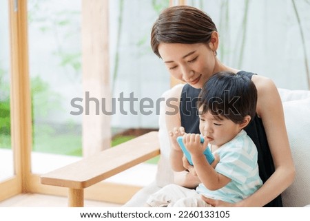 asian boy and mother using smart phone in the living room