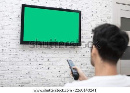 Man sitting on the couch and watching tv. Green screen concept	
